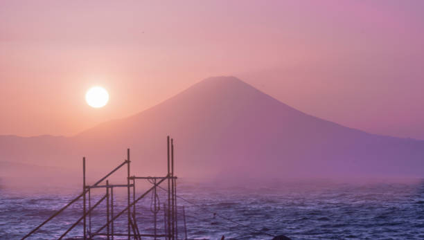 Hayama Port,Zushi Coast, Kanagawa ,Japan-March 8 ,2023: the tranquil and picturesque scene of the setting sun over the ocean, with a sailboat sailing gently and Mount Fuji in the backdrop.at dusk from Hayama Port in Zushi City, Kanagawa Prefecture, Japan, where the setting sun has infused the sky with hues of pink and gold. The tranquil waters of the ocean mirror this serene spectacle, with the radiant glow of the sun painting a soothing golden touch across the scene. At the backdrop, Mount Fuji stands tall and dignified, contributing to the grandeur of the panoramic view. Further enhancing the tranquillity of the scene, a sailboat with its white sails unfurled is seen gracefully gliding through the calm waters, propelled by the gentle whisper of the evening breeze. This picture is an embodiment of nature's exquisite beauty, emanating a profound sense of peace and serenity.