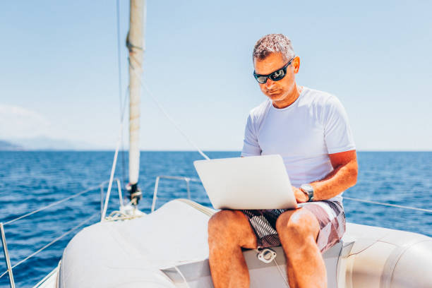 istock Businessman with laptop on sailboat 1569244845