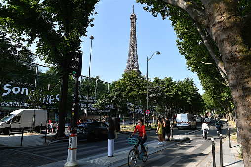 Paris, France-06 28 2023:Group of cyclists in a street of Paris, with a view of the Eiffel tower in the background, France.