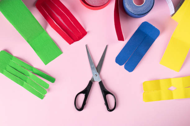 istock Colorful kinesiology tape, scissors and different shape cuts for applique on pink background, Top view 1569248621