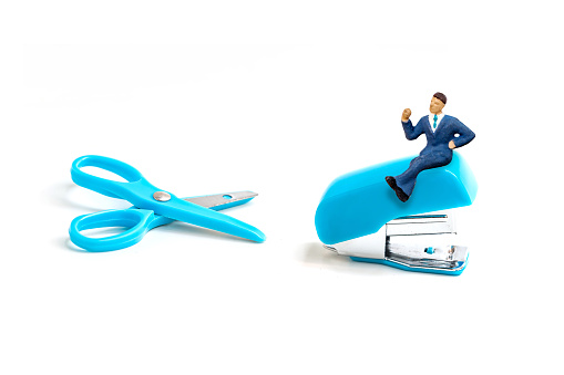 blue scissors and stapler with miniature business man  isolated on white background.