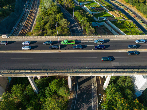 Aerial perspective on the intersection of several lanes of a highway, with several vehicles circulating