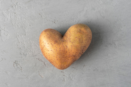 Heart shaped potatoes on a gray concrete background. Top view.