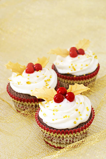 cupcakes di Natale con bacche rosse con foglie e oro - foto stock