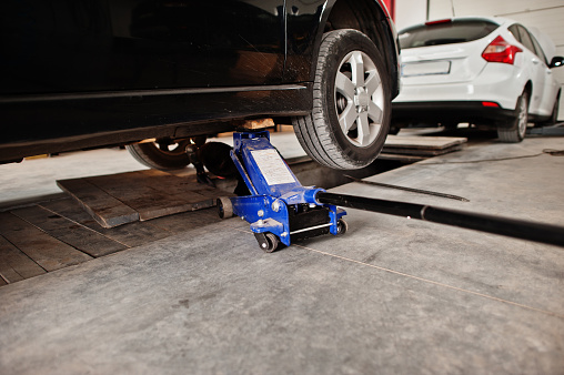 ar in maintenance at garage service station lifted with blue hydraulic floor jack for repairing.
