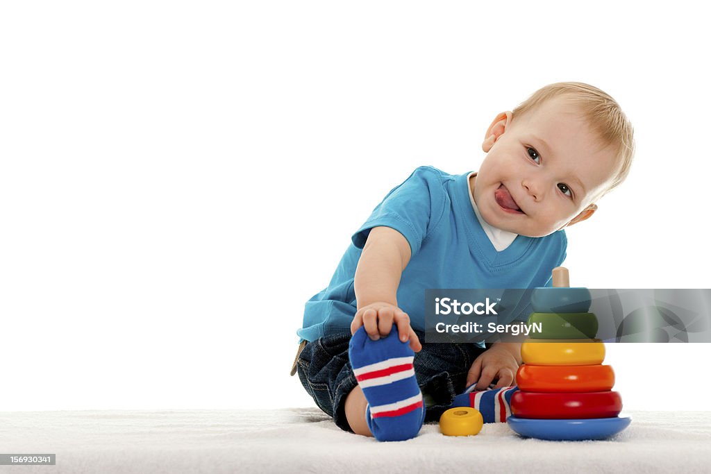 A young boy playing with the toys A little boy is playing with toys on the blanket; on the white background Baby - Human Age Stock Photo