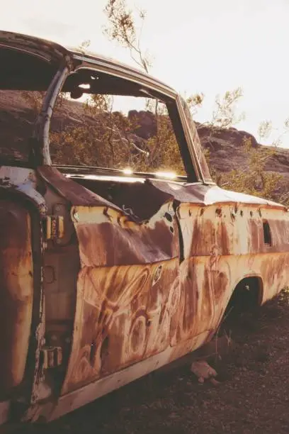 Photo of Vintage, abandoned car sits in the middle of a deserted rural landscape