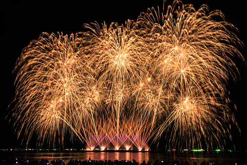 PATTAYA, CHONBURI, THAILAND Beautiful colorful fireworks night scene at Pattaya International Fireworks Festival and silhouette Group of tourist take pictures of firework show on the beach,