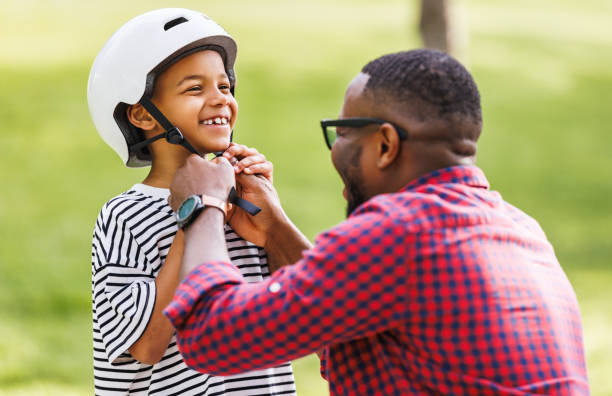 istock Happy family: father puts on son helmet for safe cycling in park 1569310241