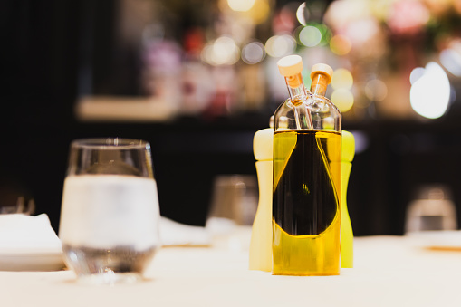 A glass bottle with olive oil and balsamic vinegar on dinner table