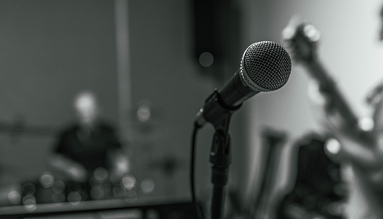 close up of a microphone during a rehearsal of a band | drummer | guitarrist | singer | music studio