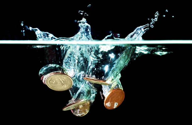 US Coins Dropped in Water on Black Close-up of a group of coins dropped in water with splash on black. Money laundering related concept. a penny saved stock pictures, royalty-free photos & images