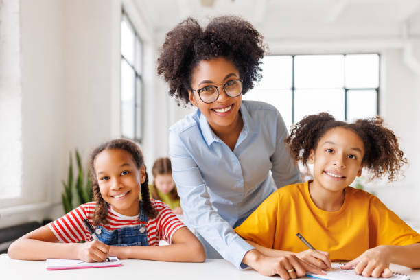 istock Teacher helping children with schoolwork 1569380470