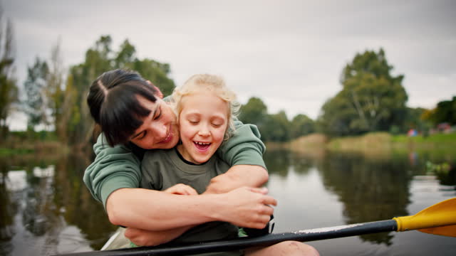 Nature, kayaking and mother hugging her child while floating on a lake by an outdoor forest. Adventure, love and young mom embracing her girl kid on paddle boat on river while on vacation or holiday.