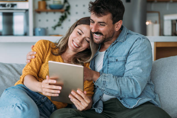 istock Smiling young couple using digital tablet at home. 1569407640
