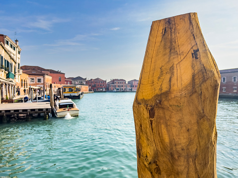 A beautiful shot of a calm seascape with a broken pillar sticking out of the water on cityscape of Murano island of Venice, in Italy. Travel destination background with copy space.