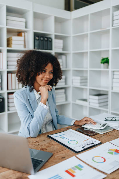 istock American African business woman using document, computer laptop, calculator, paperwork, documents, in winner and smiling Happy to be successful achievement success. finance and investment concepts 1569411416