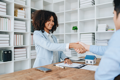 The bank's Female African american Mortgage Officers shake hands with customers to congratulate them after signing a housing investment loan agreement.