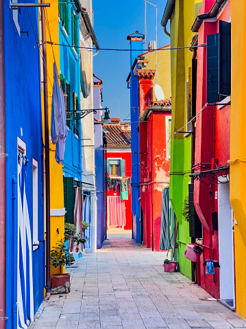Burano island, houses with bright colors and clothes hanging on lines to dry in the sun. Venetian lagoon, Venice, UNESCO world heritage site, Veneto, Italy, Europe. Beautiful ravel and tourism background on a sunny day, copy space.