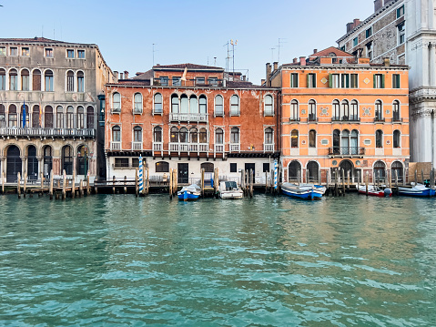 Beautiful traditional buildings and ornate gondola boats navigating or mooring in the narrow canals of Venice, in Italy. Travel destination background with copy space.