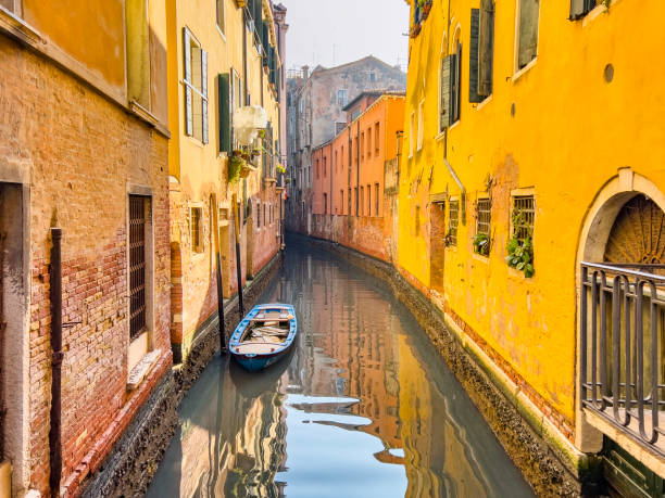 Sun falling into a narrow side canal in Venice with residential buildings. Beautiful narrow canals of Venice, in Italy. Travel destination background with copy space.