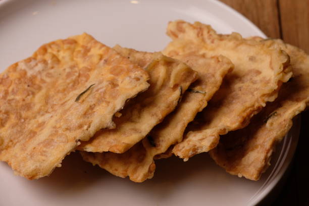 istock Keripik Tempe. Tempeh Chips is a typical Indonesian snack made from thinly sliced tempeh then fried with rice flour, coconut milk, and spices. Indonesian food. served on a white ceramic plate. Kripik. 1569432587