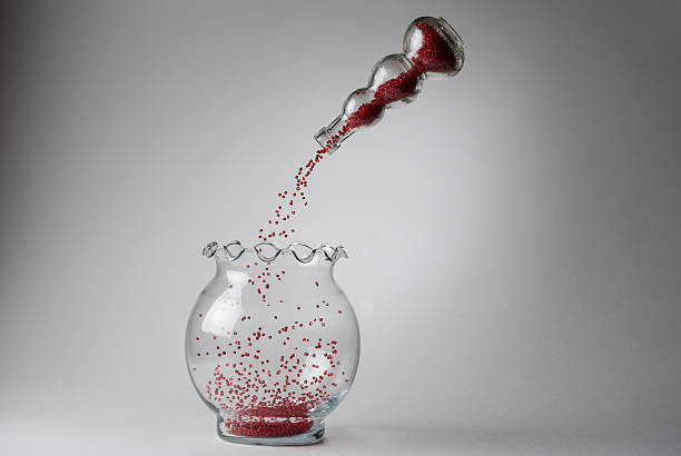Red beads falling from a levitated vase on white background stock photo