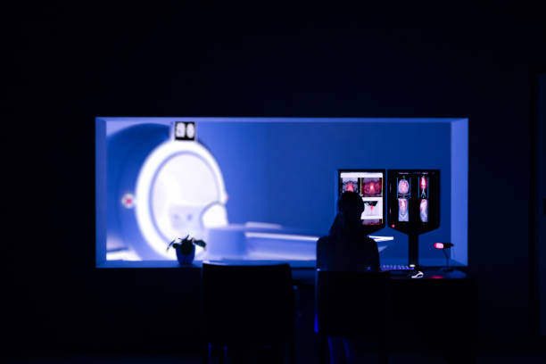 istock In Control Room Radiologist Diagnosis while Watching Procedure and Monitors Showing Brain Scans Results, In the Background Patient Undergoes MRI or CT Scan Procedure.3D rendering . 1569448903