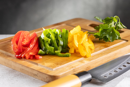 Colorful bell peppers sliced on cutting board.