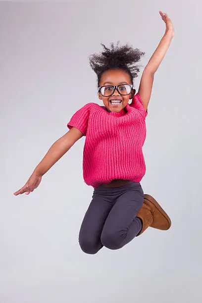 Photo of A portrait of a young girl jumping up and making a pose