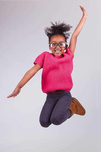 a portrait of a young girl jumping up and making a pose - happy slowmotion bildbanksfoton och bilder