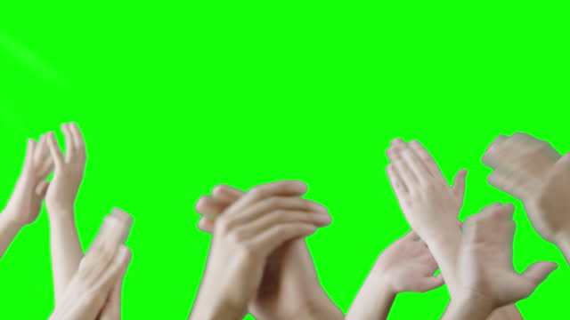 Group of individuals gather closely together, clapping hands rapidly in front of green screen.