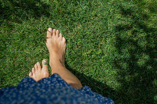 woman legs walking on green grass