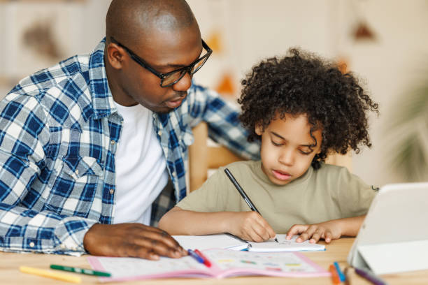 istock Ethnic dad helps son to do homework at home 1569470954