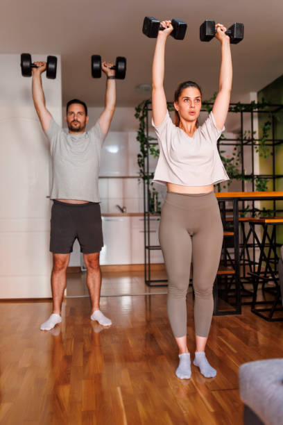 istock Couple working out at home lifting weights 1569498450