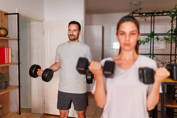 istock Couple lifting weights while working out together at home 1569500029