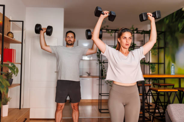 Couple doing biceps exercises with dumbbels stock photo