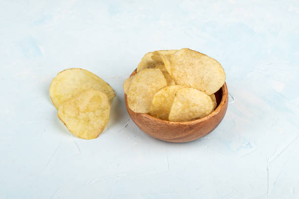 istock Crispy potato chips in a wooden bowl and on a blue background. 1569503245