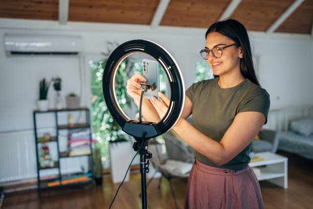 istock Female influencer vlogging through mobile phone with ring light at home 1569506256