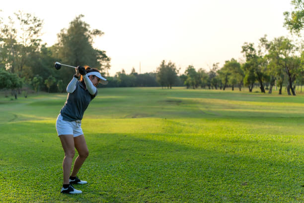 golfer women sport course golf ball fairway. people lifestyle woman playing game golf swing tee of on the green grass sunset background. asian female player game shot in summer. - golf golf swing putting cheerful imagens e fotografias de stock