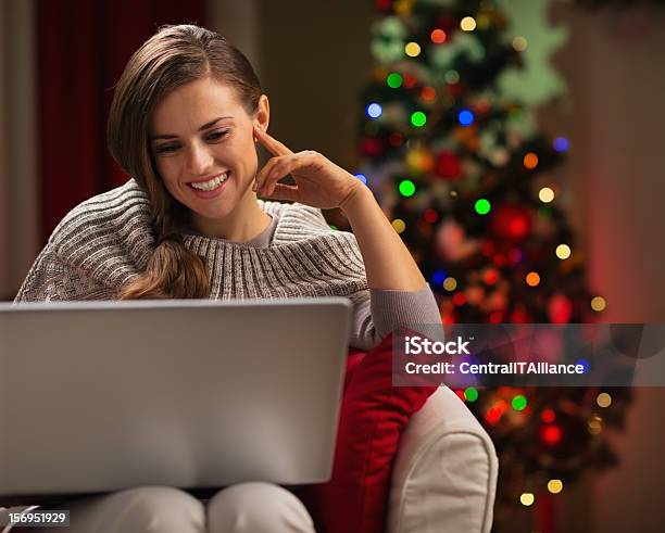 Happy Woman Looking In Laptop Near Christmas Tree Stock Photo - Download Image Now - Adult, Celebration, Christmas