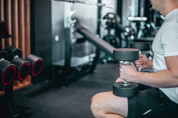 istock Young man training in gym with dumbbells 1569531017
