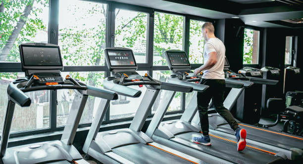 istock Young man using the treadmill in the gym 1569533625
