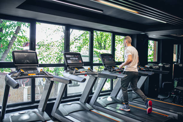 istock Young man using the treadmill in the gym 1569535683