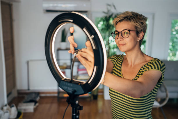 istock Female influencer vlogging through mobile phone with ring light at home 1569536204