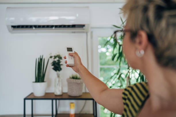 istock Woman turning on air conditioner 1569538335