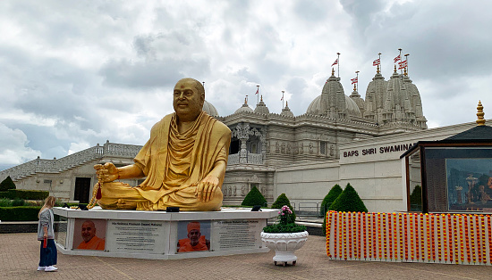 BAPS Shri Swaminarayan Mandir  with golden Buddha out side the large ornately decorated Hindu temple - it was the largest temple outside of India in 2010 - it is now the largest in Europe