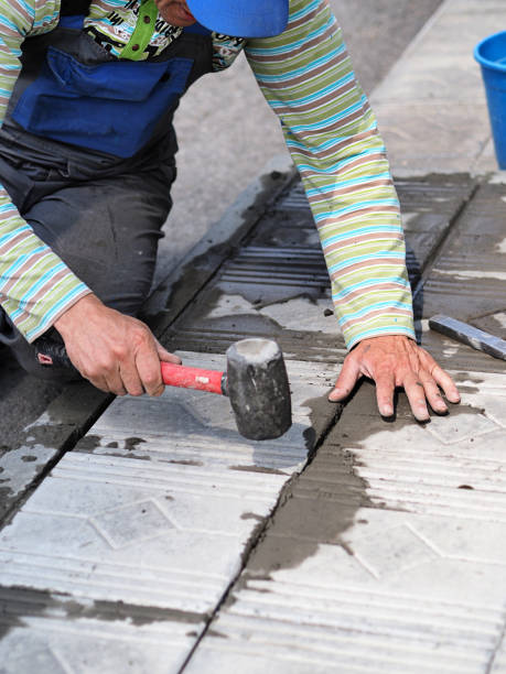 carreleur posant des carreaux sur les fondations du bâtiment à l’extérieur. mains d’un travailleur avec gros plan marteau. - contracting repairing residential structure vertical photos et images de collection