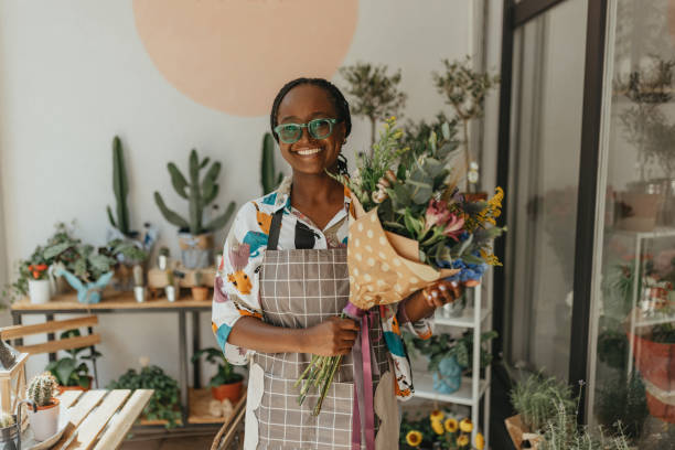istock Young black entrepreneur, aged 26, sells multi-colored flowers and decorations in-store. 1569565472