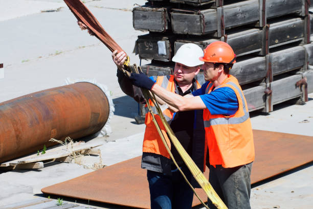 istock Two helmeted slingers attach load to slings outside on summer afternoon. Loading cargo. 1569569072